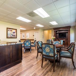 A well-lit dining area with elegant chairs and tables, featuring wood flooring and decorative artwork.