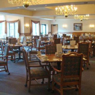 An empty dining room with neatly arranged tables and chairs under elegant lighting.