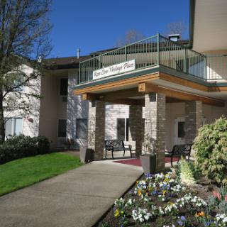 The welcoming entrance of a residential building, surrounded by colorful flowers and greenery.