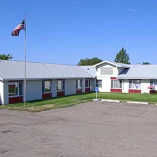 A one-story school building with a flagpole outside on a clear day.