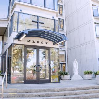 Entrance of a modern building with glass doors and a statue beside it.