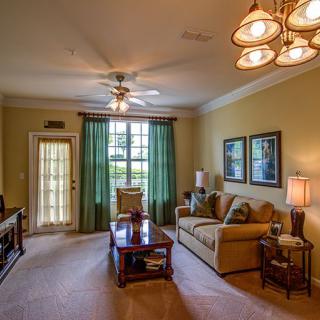A cozy living room with comfortable seating, a ceiling fan, and decorative touches.