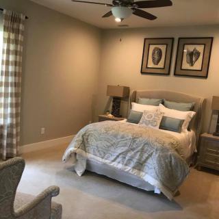 A cozy and well-decorated bedroom with neutral tones, featuring a comfortable bed, matching lamps, and plaid curtains.