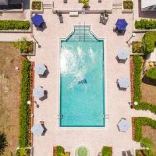 Aerial view of a swimming pool surrounded by lounge chairs and umbrellas in a landscaped patio area.