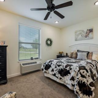 A cozy bedroom with a neatly made bed, ceiling fan, and tasteful decor.