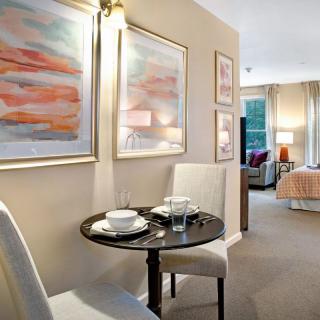 A cozy dining area within an apartment featuring a small table set for two, adjacent to a bedroom.