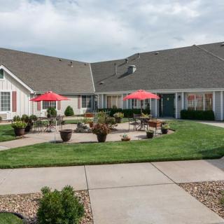 A well-maintained courtyard with outdoor seating and red umbrellas in a residential community.