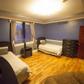 A cozy bedroom with two single beds, featuring blue walls and a hardwood floor.