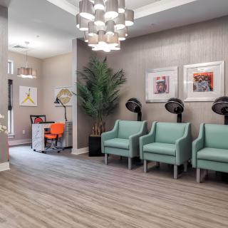 A modern hair salon waiting area with stylish chairs and artwork.