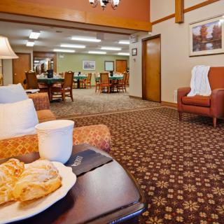 A cozy hotel lobby featuring comfortable seating areas with a plate of pastries and a cup of coffee in the foreground.