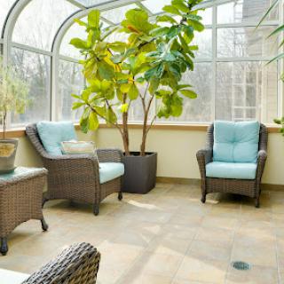 A bright and inviting sunroom featuring comfortable seating, lush greenery, and abundant natural light.