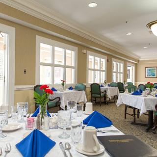 A well-set dining room with elegant table settings and blue napkins.