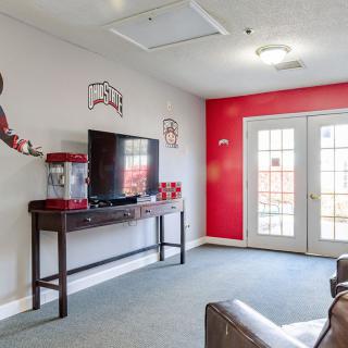 A cozy living room with a TV, popcorn machine, and red accent wall.