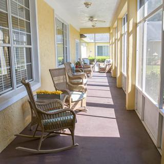 A bright porch with several rocking chairs and large windows letting in sunlight.