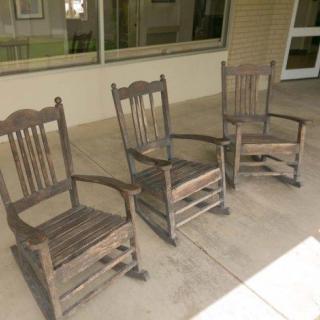 Three wooden rocking chairs lined up on a porch.