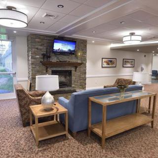 A cozy living room with a stone fireplace, comfortable seating, and a mounted television.