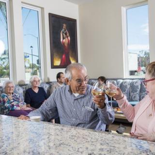 A group of elderly people enjoying a social gathering at a restaurant, sharing a toast with wine.