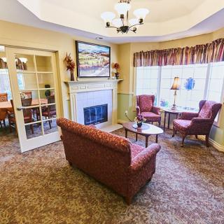 Cozy living room with a fireplace, sofa, and chairs near large windows.