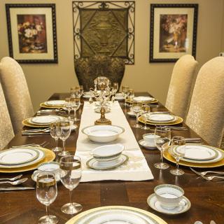A formal dining table set with elegant plates and glassware, prepared for a sophisticated dinner.