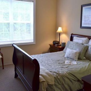 A cozy bedroom with a wooden bed, bedside table, and lamp.
