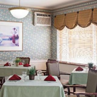 A cozy dining room with neatly set tables, featuring elegant decor and warm lighting.