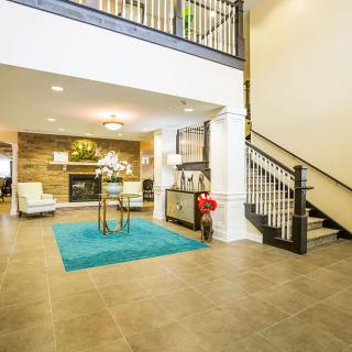 A modern and cozy living area featuring a staircase, decorative rug, and fireplace.