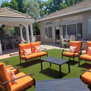 A cozy outdoor patio with orange-cushioned seating and a gazebo in the backyard.