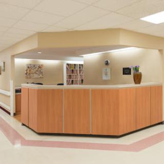 A modern reception area in a hospital featuring a wooden front desk and soft lighting.