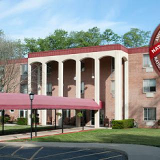 A modern residential building featuring elegant columns and a protective canopy at the entrance.