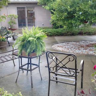 A peaceful patio setting featuring outdoor furniture and lush greenery.