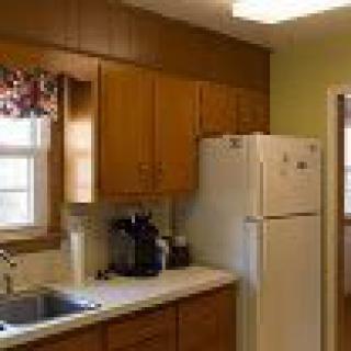 A cozy kitchen with wooden cabinets, a refrigerator, and a sink.