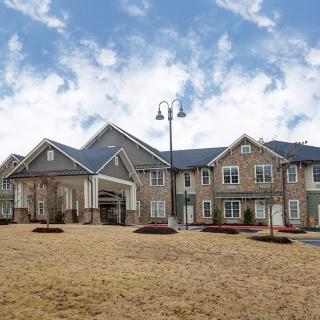 A modern residential building with landscaped surroundings under a blue sky.