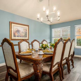 Elegant dining room with a large wooden table, upholstered chairs, and a modern chandelier.