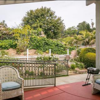 A cozy patio with wicker chairs and a small grill overlooking a lush garden.