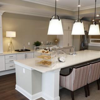 A modern kitchen featuring a large island with pendant lighting and bar stools, surrounded by stylish cabinetry and appliances.