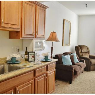 A cozy living space with a kitchen area, featuring wooden cabinets and a comfortable seating arrangement.