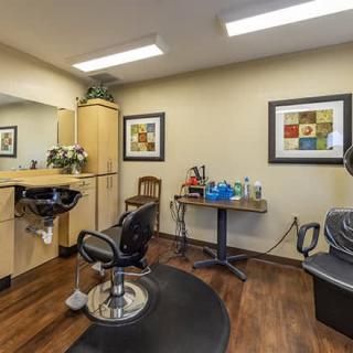 A cozy hair salon interior with chairs, mirrors, and artwork on the walls.