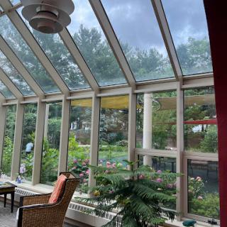 A sunroom adorned with lush plants and a panoramic view of the garden, inviting natural light.