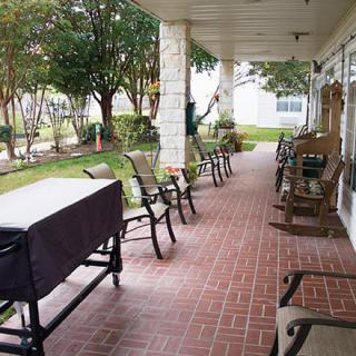 A covered porch with multiple chairs overlooking a garden space.
