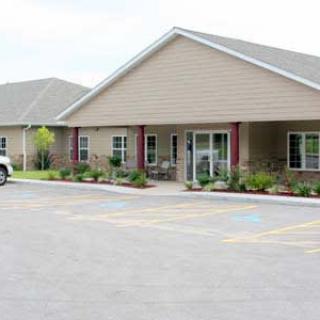 A view of a building with a parking lot and landscaped entrance.