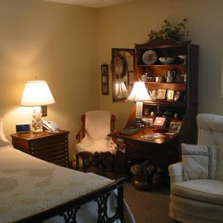 A cozy and inviting bedroom setting featuring warm lighting, comfortable furniture, and decorative shelves.