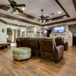 Spacious living room with leather seating, wooden floors, and a mounted television.