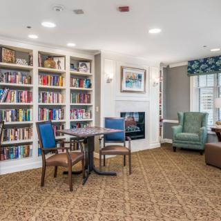 A cozy library reading area with bookshelves, comfortable chairs, and a fireplace.