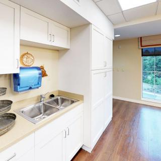 A clean kitchen area with white cabinets, a double sink, and hardwood flooring.