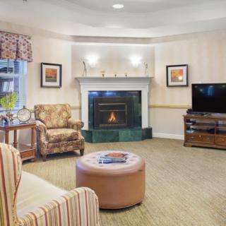 A cozy living room with a fireplace, armchairs, and a television.