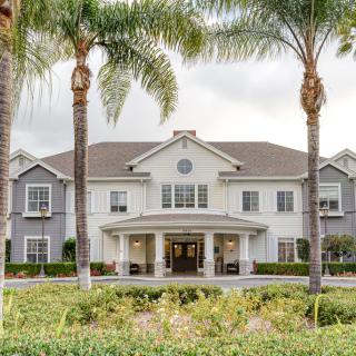 A white residential building with palm trees in front.