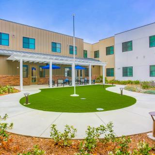 A modern building with a well-maintained courtyard featuring a circular lawn and landscaping.