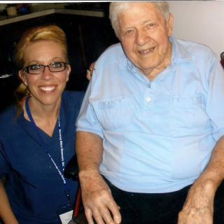 An elderly man smiling with a nurse by his side.