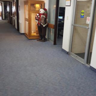 A clown statue standing in a hallway, next to an office entrance.