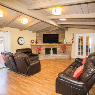 A cozy living room with leather sofas, a wall-mounted TV, and a decorative fireplace.
